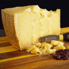 Parmigiano Reggiano stagionato oltre 18 mesi con coltellino a mandorla su tagliere di legno